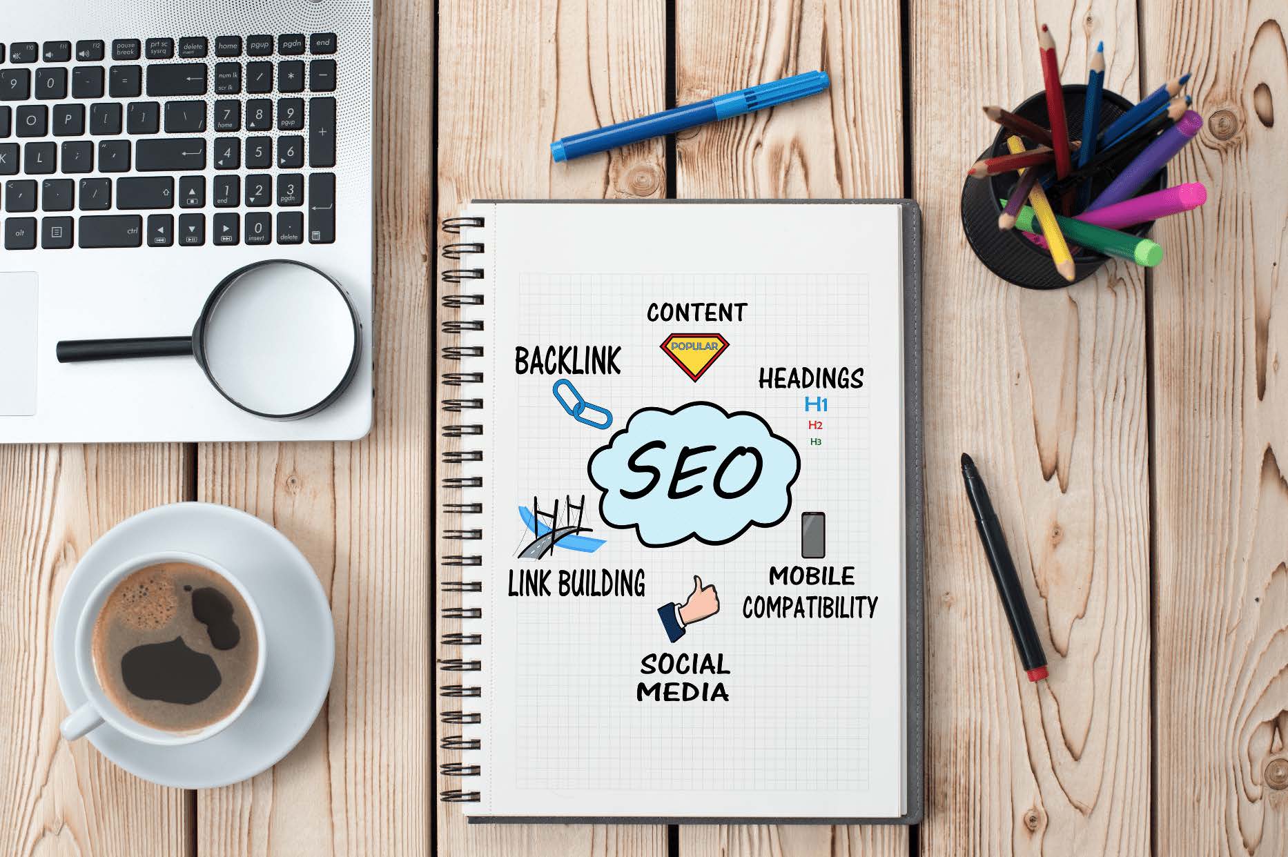 Enjoying hot cup of coffee while studying SEO booklet with laptopp and color pens for highlighting